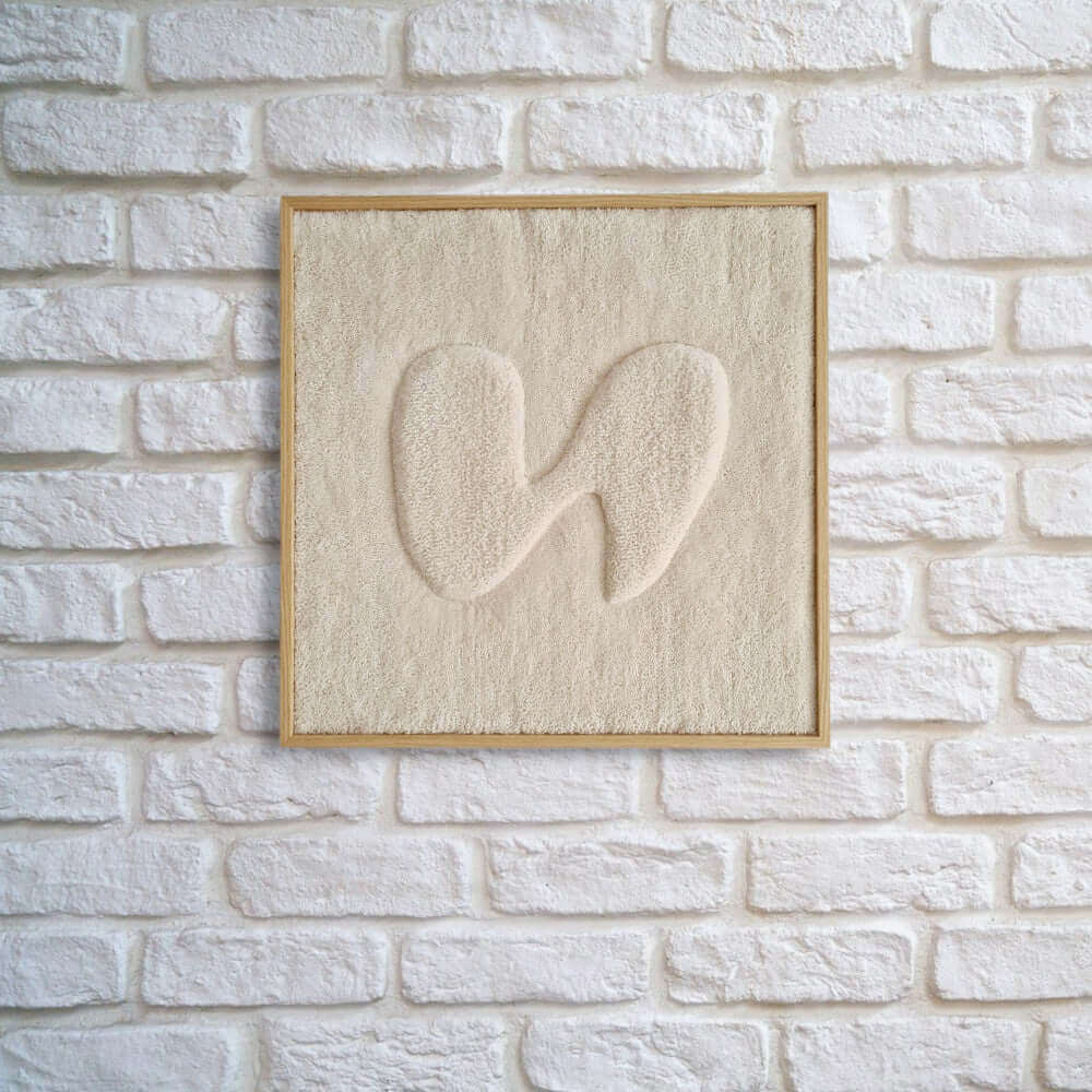 gerahmter Wandteppich im Eichholz Echtholzrahmen mit organischer Form in 3D Farbe beige an weiß gemauerter Wohnzimmerwand