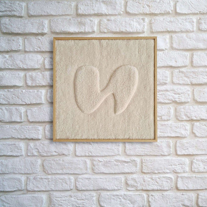 gerahmter Wandteppich im Eichholz Echtholzrahmen mit organischer Form in 3D Farbe beige an weiß gemauerter Wohnzimmerwand